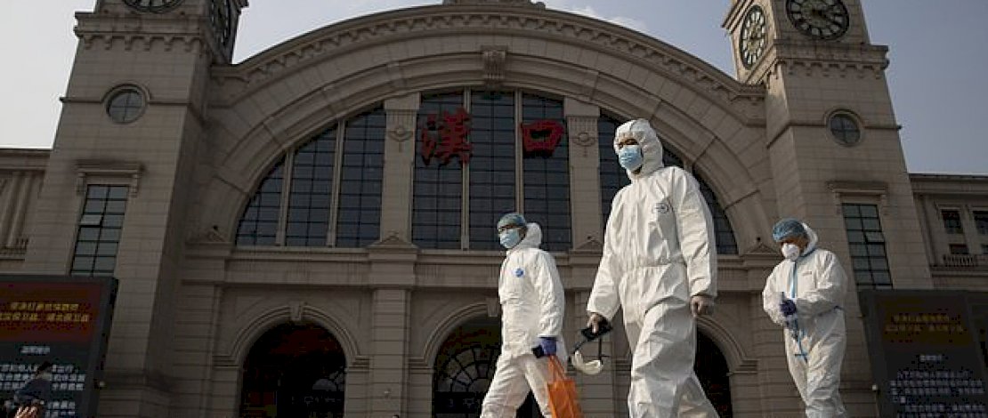 Para pekerja dengan pakaian pelindung berjalan melewati stasiun kereta api Hankou di Wuhan di provinsi Hubei China, April 2020.
