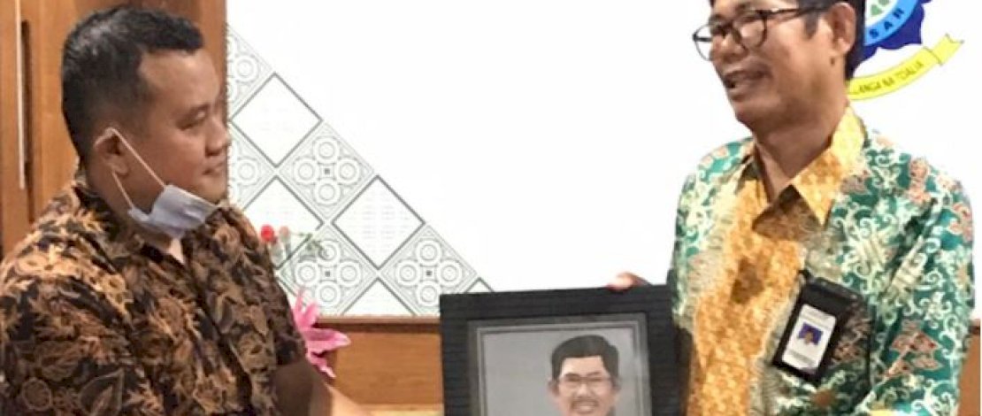 Direktur Bukamatanews.di, Muhammad Taufiq memberikan bingkisan karikatur kepada Direktur Poltekpar Makassar, Muhammad Arifin. 