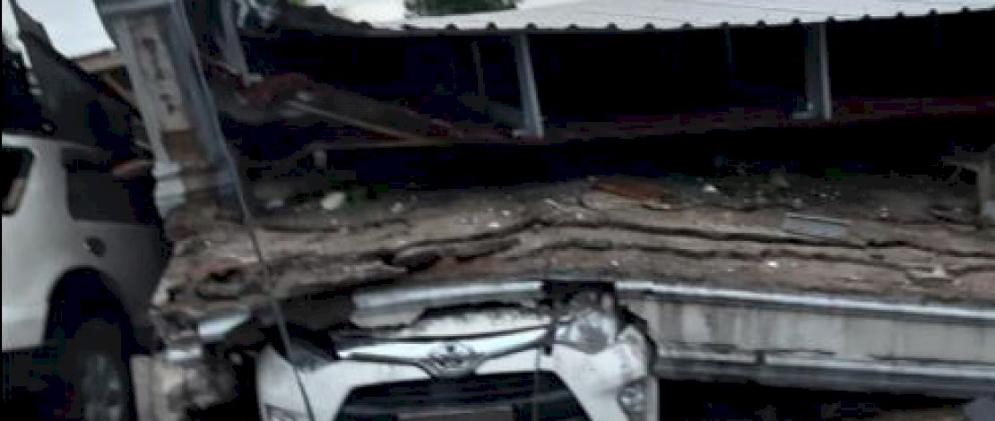 Sebuah rumah rubuh dan reruntuhannya menimbun sebuah mobil di Mamuju.