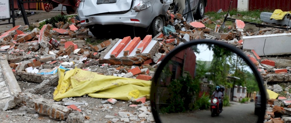 Warga melintas di tengah reruntuhan bangunan yang rubuh akibat gempa M 6,2 di Kota Mamuju, Sulawesi Barat, Minggu 17 Januari 2020. FOTOGRAFER/ ZUL KIFLI