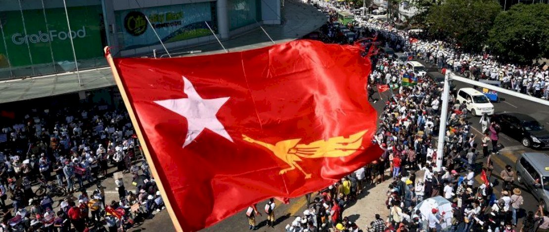 Bendera partai Liga Nasional untuk Demokrasi Suu Kyi berkibar di atas pengunjuk rasa di Yangon. (Getty)