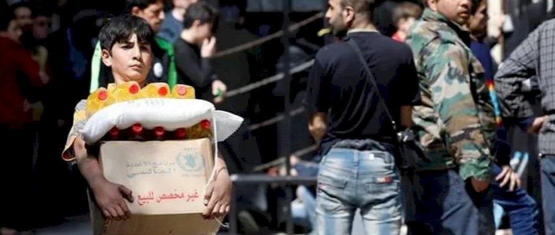 Seorang anak laki-laki memegang sekotak bantuan makanan yang diterima dari Program Pangan Dunia di distrik Kalasa, Aleppo, Suriah 10 April 2019. (Foto: REUTERS / Omar Sanadiki) Seorang anak laki-laki memegang sekotak bantuan makanan yang diterima dari Program Pangan Dunia di distrik Kalasa, Aleppo, Suriah 10 April 2019. (Foto: REUTERS / Omar Sanadiki)