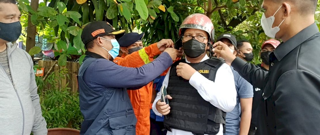 Petugas memasangi Danny rompi anti peluru dan helm.