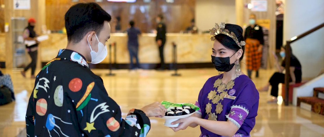 Karyawati Claro melayani tamu dengan memakai baju adat.