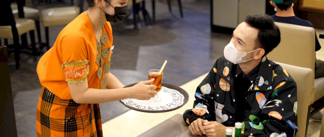 Karyawati Claro melayani tamu dengan memakai baju adat.