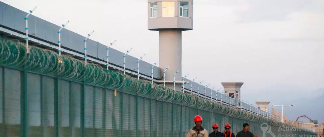 Para pekerja berjalan di pagar pembatas pusat pendidikan keterampilan kejuruan di Dabancheng di Daerah Otonomi Uighur Xinjiang, China, pada 4 September 2018. (Reuters)
