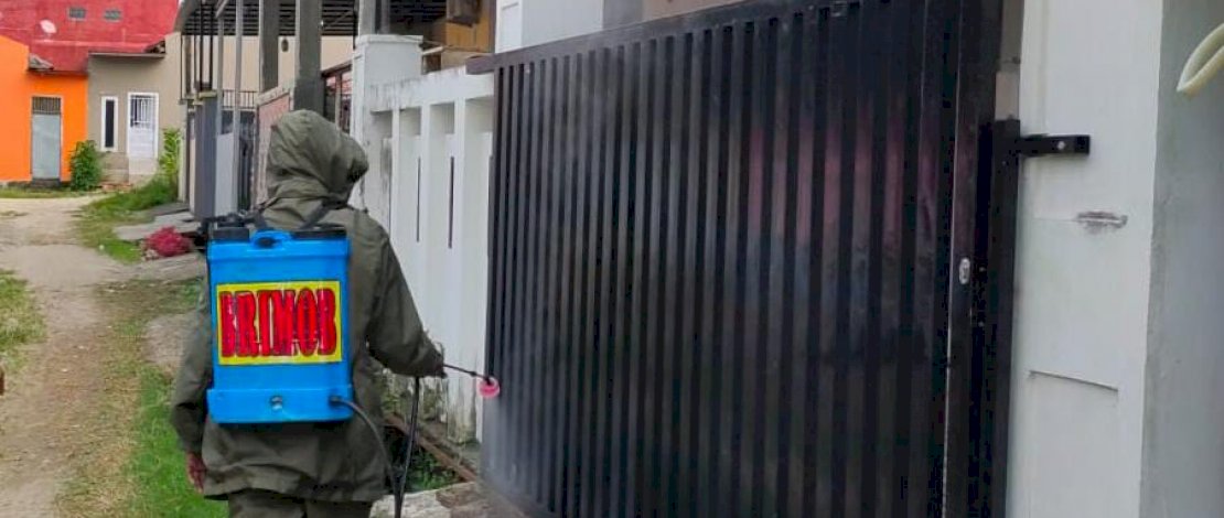 Personel Yon C Pelopor Brimob Polda Sulsel menyemprotkan disinfektan ke halaman rumah warga.