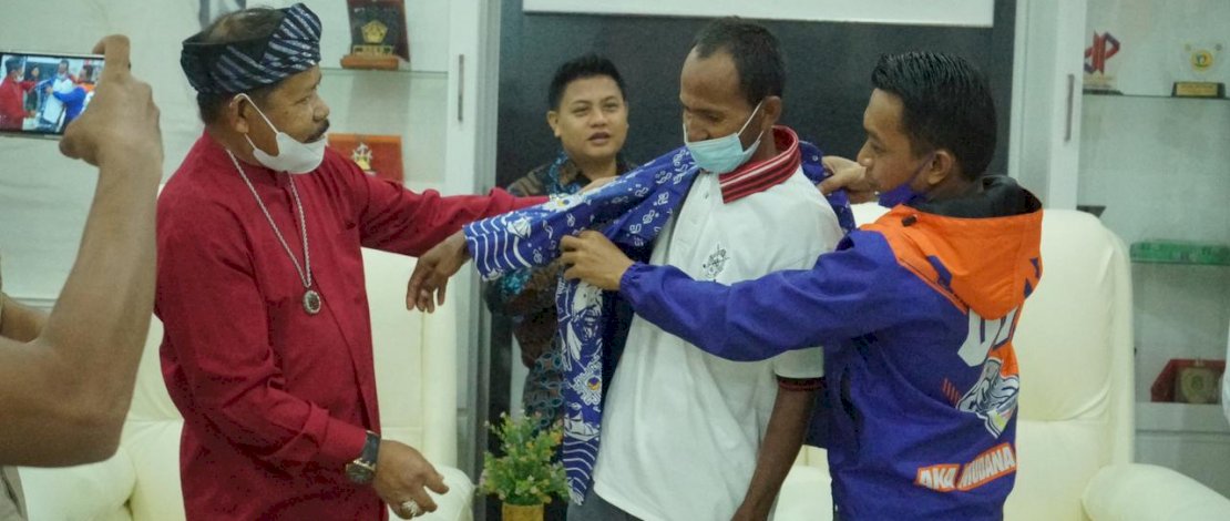Sekretaris NasDem Sulsel, Syaharuddin Alrif memakaikan batik kepada Samidin, pria Buton yang nekat mengarungi laut pulang ke Buton dengan mendayung perahu karena tak punya ongkos. 