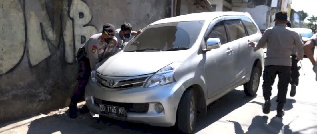 Kapolres Pelabuhana dan anggotanya mengevakuasi sebuah mobil yang terperosok ke dalam parit.