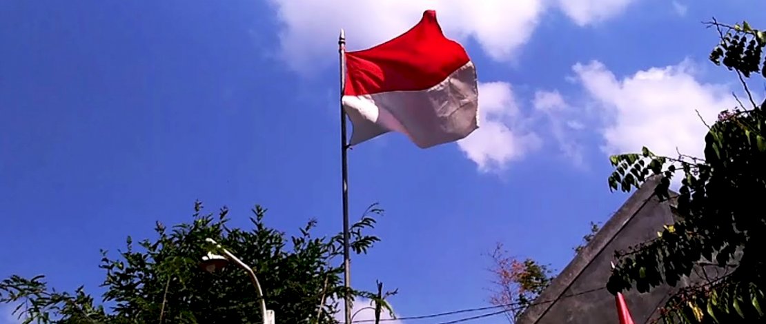 Ilustrasi bendera Merah Putih berkibar di ujung tiang tertinggi.