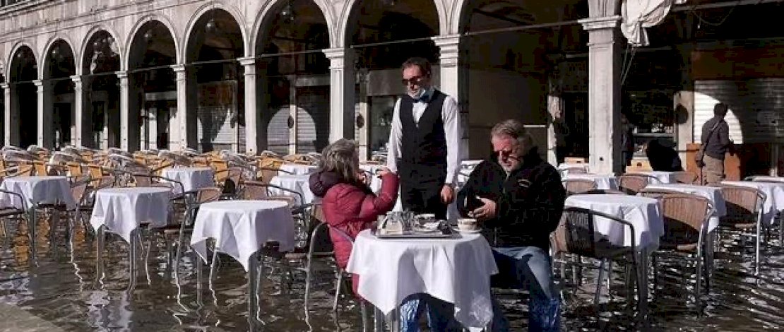 warga tampak asik menikmati secangkir kopi di tengah banjir di Kota Venesia, Italia. (Foto: Reuters).