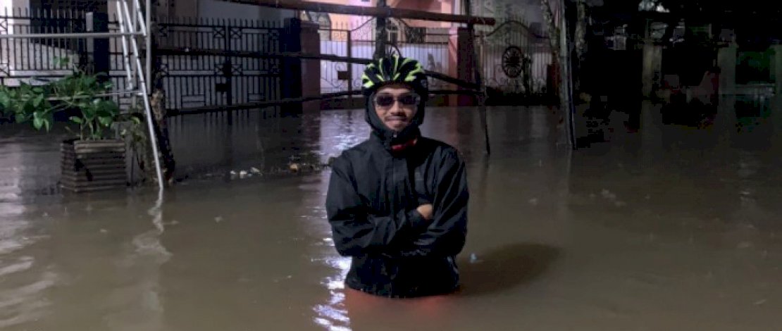 Warga Puri Pattene, Andi Muh Yunus, berdiri di depan rumahnya yang kebanjiran. 