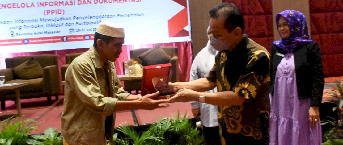 Ketua Komisi Informasi Provinsi Sulsel, Pahir Halim, menyerahkan plakat kepada Iskandar, Pejabat PPID Dinas PMD Lutra.