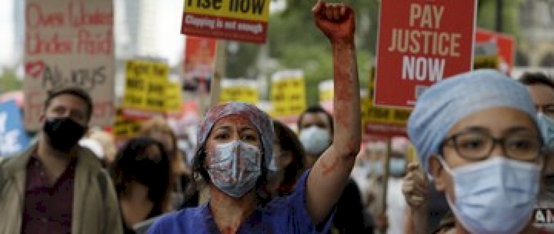 Anggota perawat dan staf Layanan Kesehatan Nasional Inggris (NHS) melakukan aksi di tengah penyebaran penyakit COVID-19, di luar Downing Street di London, Inggris. (AP/Kirsty Wigglesworth)