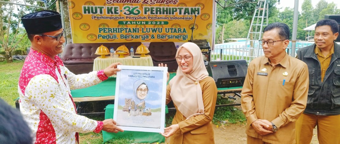 Ketua DPD Perhiptani Luwu Utara, Made Sudana, menyerahkan karikatur kepada Indah Putri Indriani, pada Puncak Perayaan HUT Ke-36 Perhiptani yang dipusatkan di Bukit Tirosoe, Kecamatan Baebunta.
