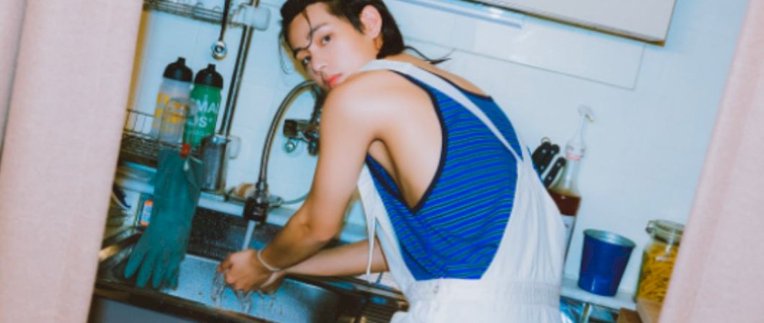 Kim Taehyung (V) menunjukkan dirinya sedang mencuci piring dalam salah satu foto promosi album solo perdananya 'Layover'