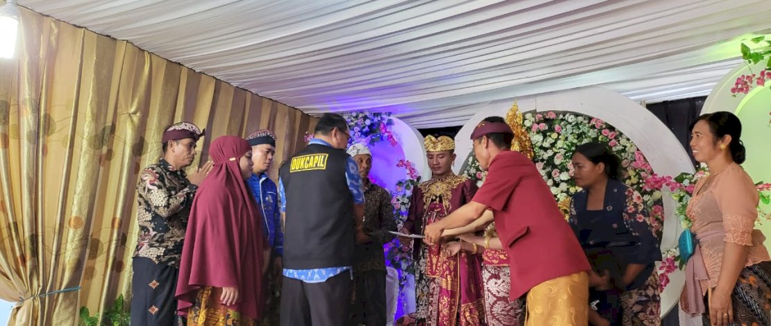 Kepala Dinas Kependudukan dan Pencatatan Sipil (Disdukcapil) Kabupaten Luwu Utara, Muhammad Kasrum, menyerahkan Akta Perkawinan Keluarga Umat Hindu Bali di Desa Mekarjaya, Kecamatan Mappedeceng.