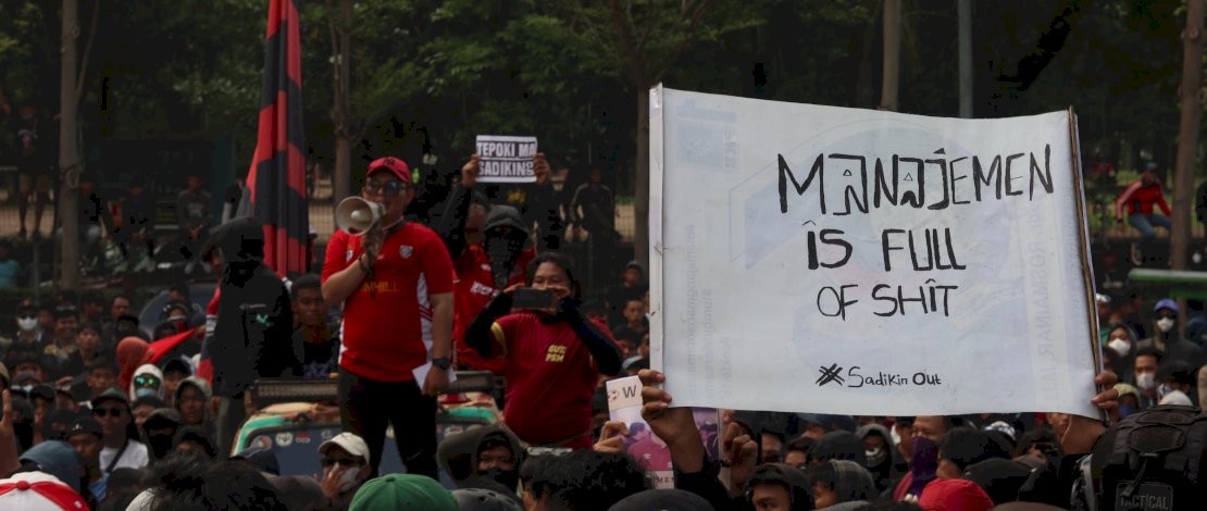 Para pengunjuk rasa membawa spanduk bertulis 'Manajemen Is Full of Shit' dengan arti 'Manajemen penuh dengan kotoran' dengan hastag #Sadikin Out.