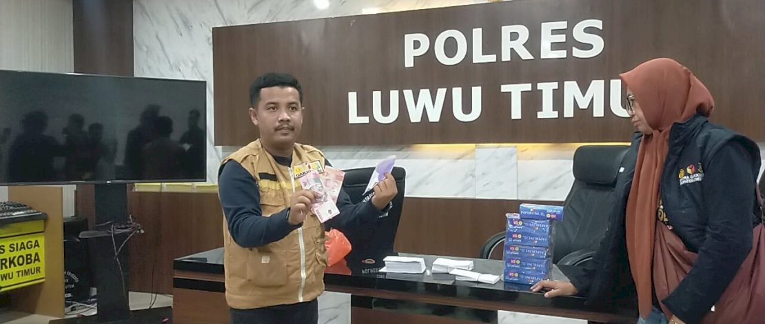 Komisioner Bawaslu Luwu Timur memperlihatkan uang dalam amplop yang diamankan dari dalam mobil yang diakui milik Anggota DPRD Golkar.