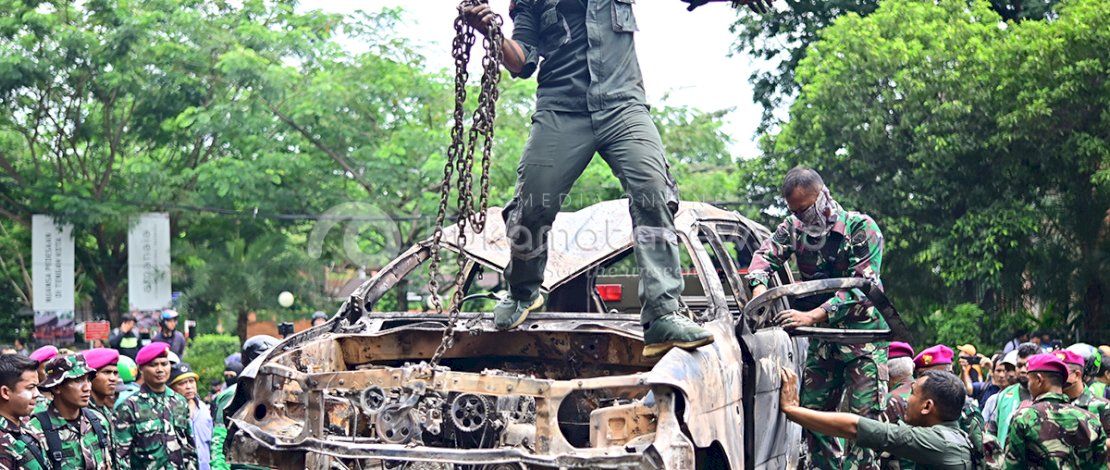 Personel TNI bersama warga dan massa aksi bergotong royong mengevakuasi delapan unit mobil yang hangus terbakar akibat kericuhan sehari sebelumnya.
Foto: Vkar Sammana