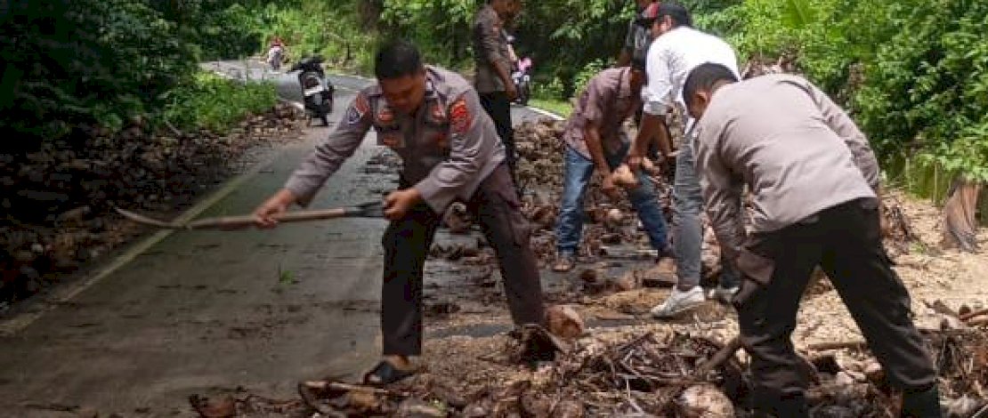 Personel Polres Selayar bersama warga melakukan pembersihan badan jalan poros Benteng - Appattanah yang tertutup material lumpur, batu, dan sampah, akibat hujan dengan intensitas tinggi yang mengguyur wilayah Kecamatan Bontosikuyu, Senin, 8 Desember 2025.