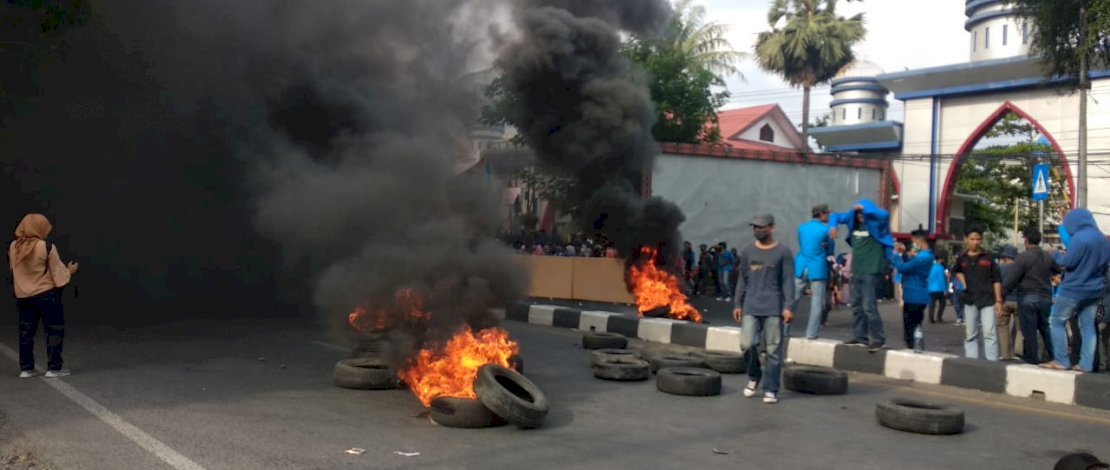 Mahasiswa Unismuh membakar ban bekas di depan kampus mereka.