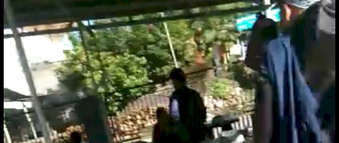 Seorang pria mengenakan helm, mengusir pria bersorban yang sedang beristirahat di minimarket. 