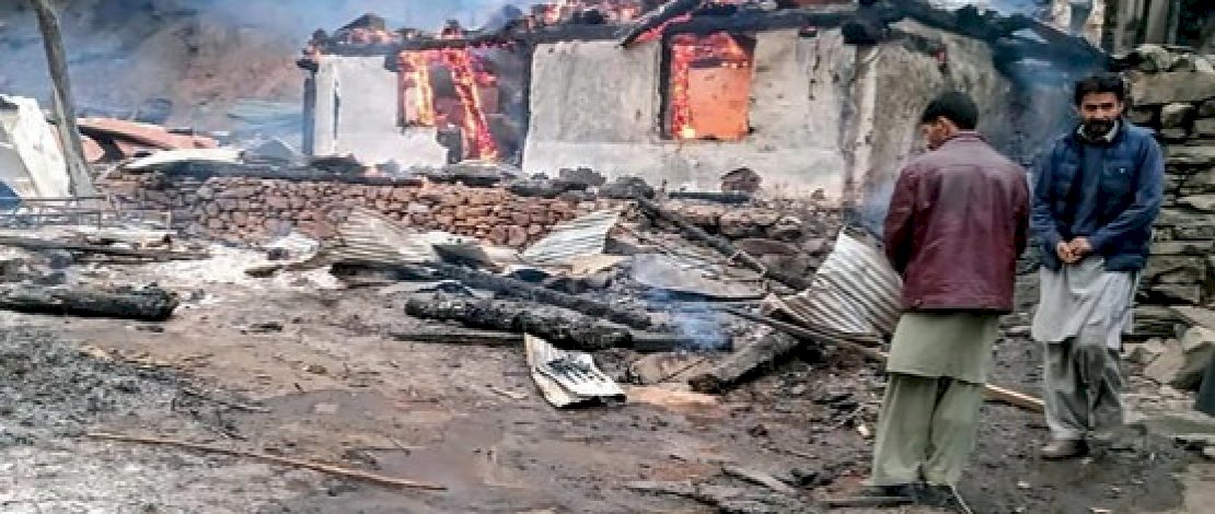 Penduduk lokal berdiri di samping rumah yang terbakar setelah bentrokan ntara pasukan Pakistan dan India di desa Tehjain, Kashmir, yang dikelola Pakistan, 13 November 2020