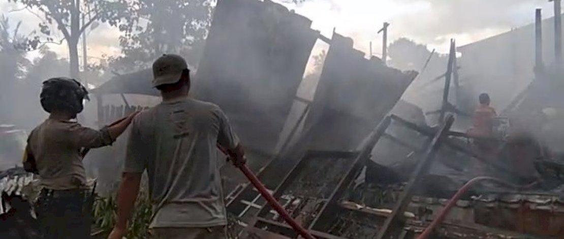 Pemadam bersama petugas kepolisian dan warga, berusaha memadamkan api.