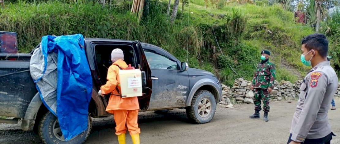 Satgas Covid-19, menyemprotkan disinfektan ke kendaraan yang lewat di Posko Minage.