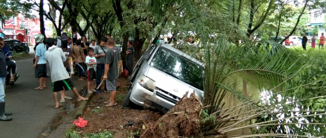Sebuah mobil silver nyaris masuk ke sungai usai menghindari tabrakan dari sepeda motor yang menyalip.
